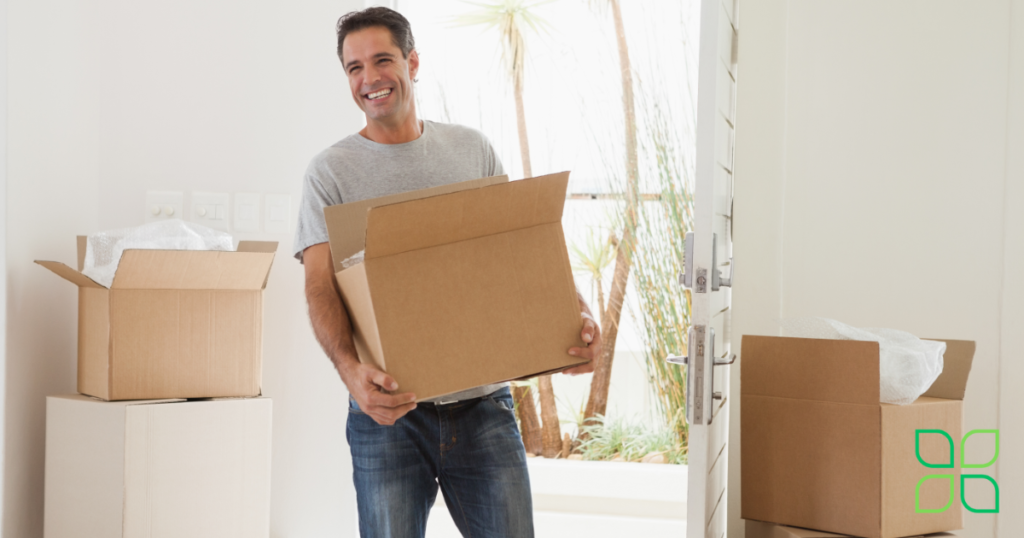 young man smiling while carrying boxes